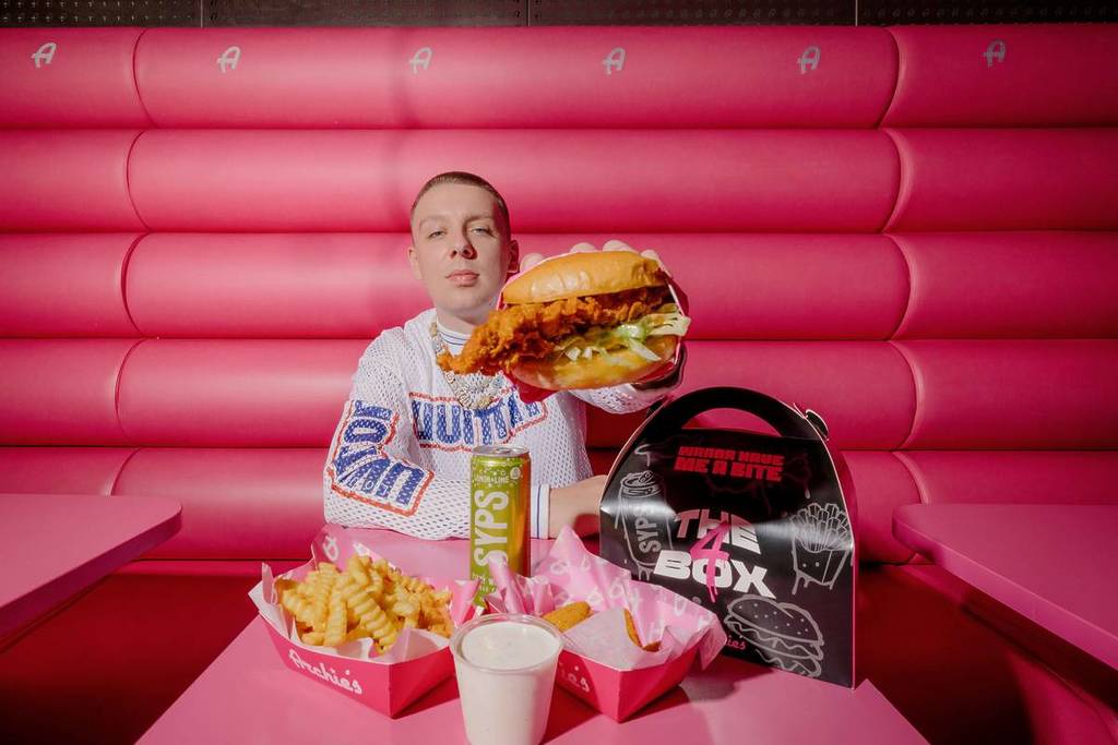 aitch holding nashville chicken burger next to the 4 box at archie's