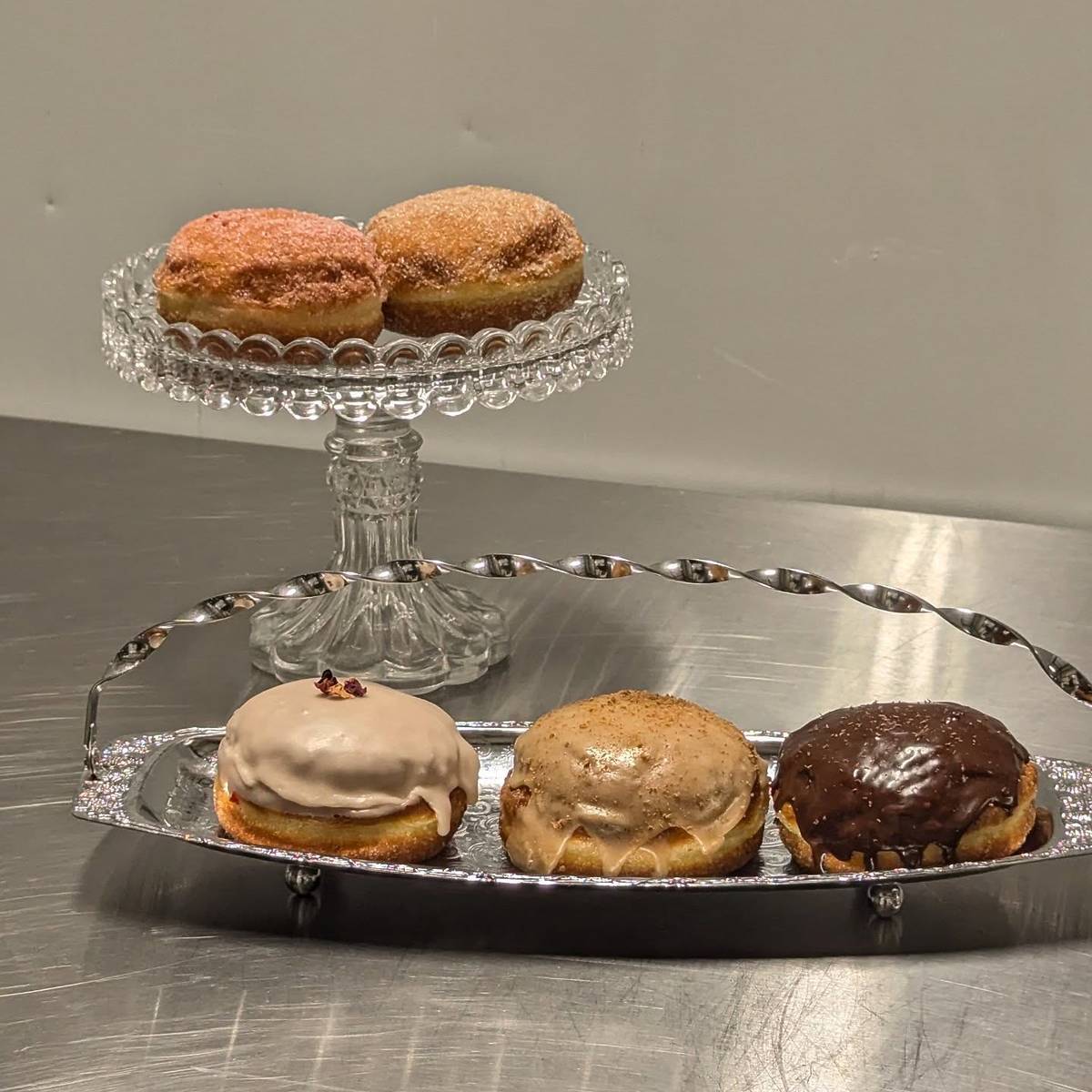 selection of doughnuts by sticky fingers in stockport with two on glass tier and three on silver tray