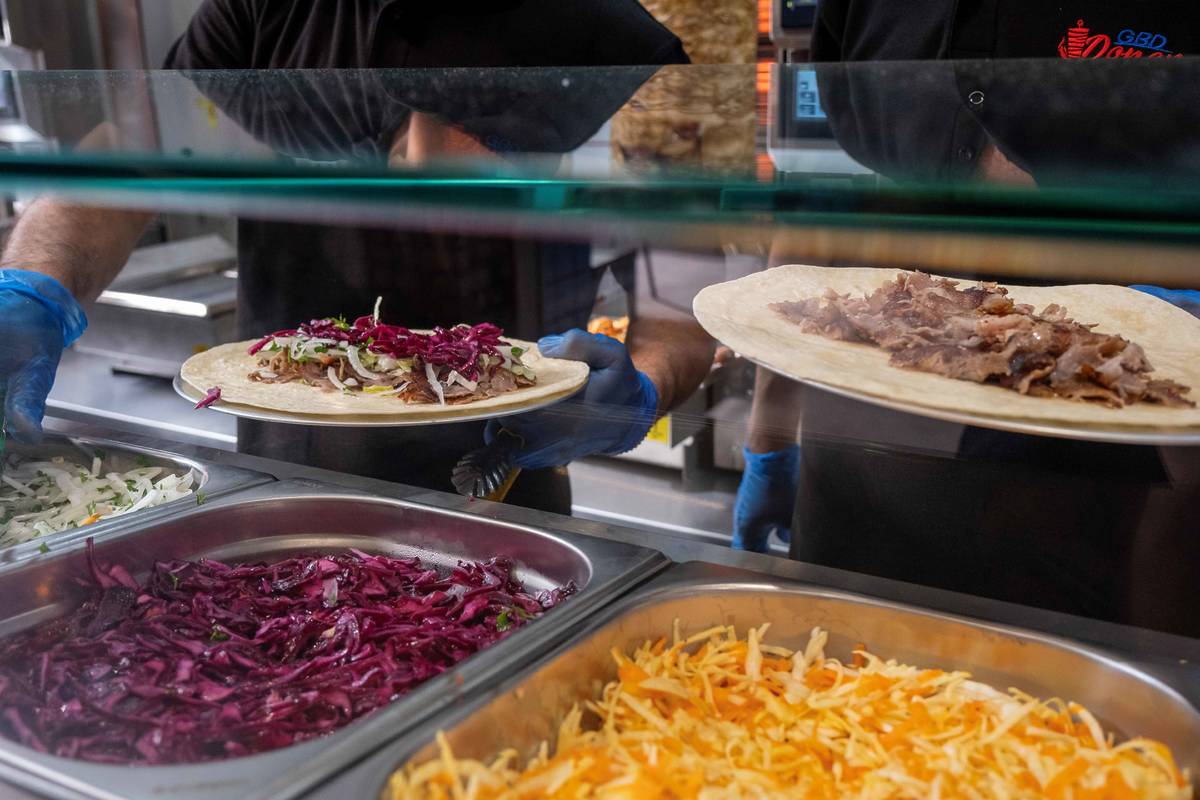 staff making doner kebabs to order with salad ingredients in front on counter