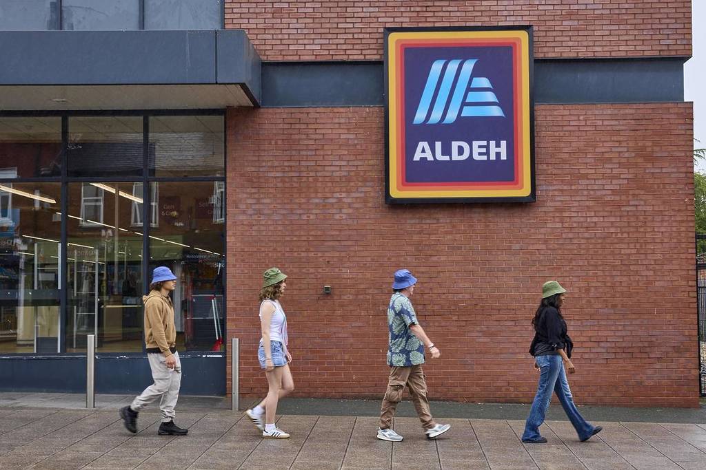people in bucket hats walking past aldeh sign oasis reunion petition to make permanent