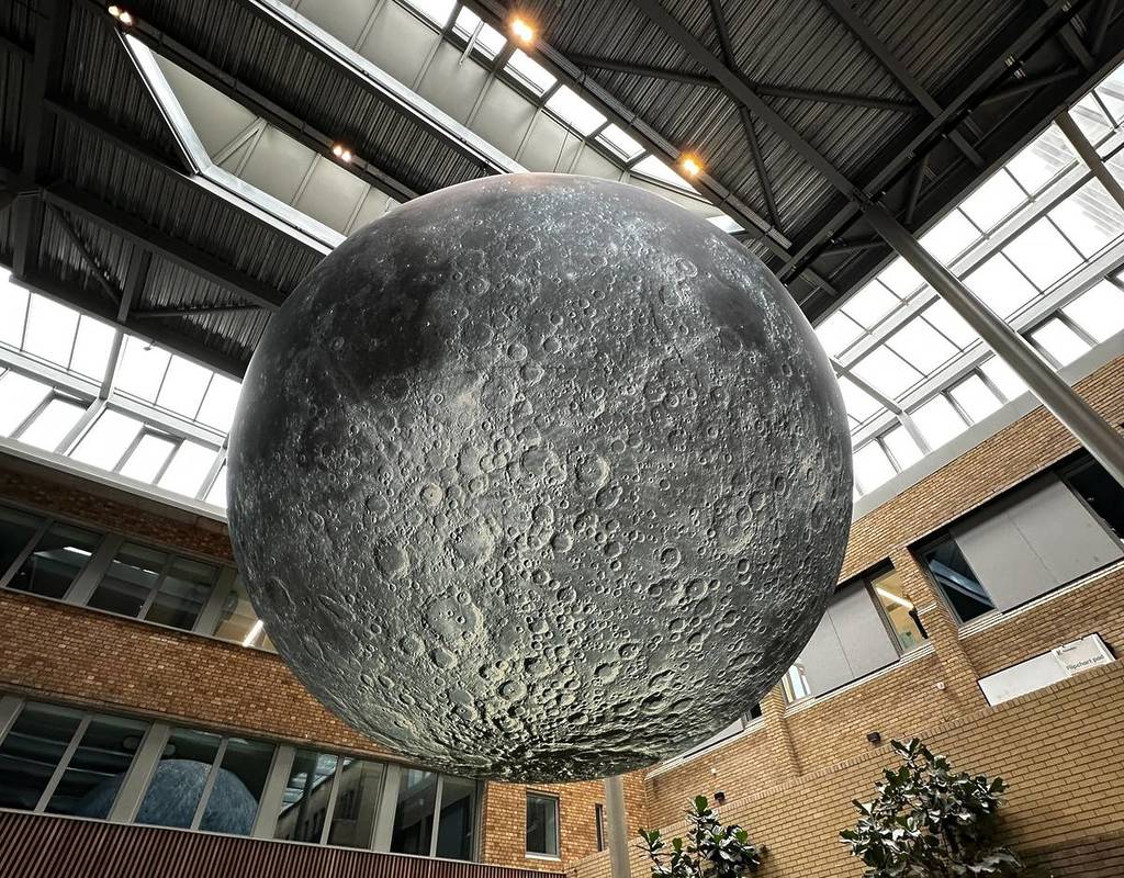 huge museum of the moon sculpture suspended from ceiling inside glasshouse at alderley park