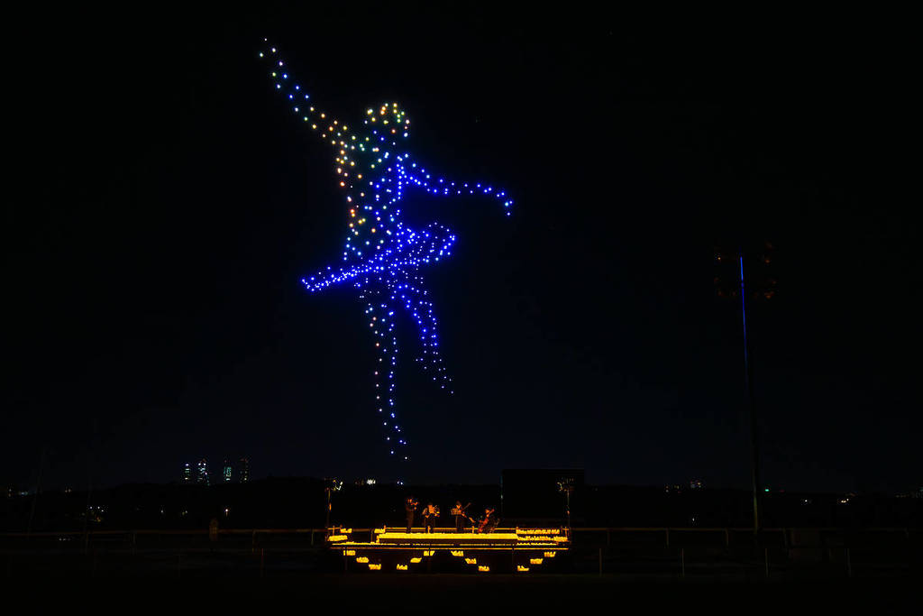 a drone art show features a dancing ballerina in the sky while a string quartet performs among candles