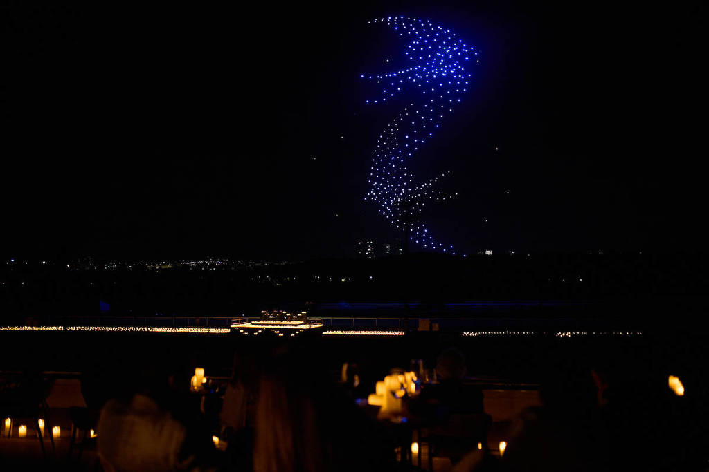 a drone art show features swallows swooping in the sky while a string quartet performs among candles