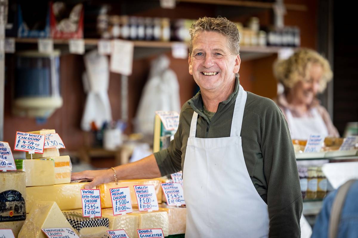 man next to cheese selection at bury market