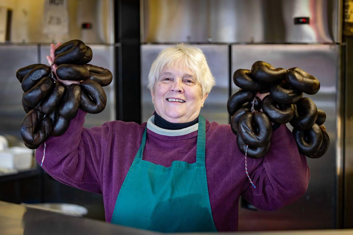 black puddings held up by woman at bury market stall