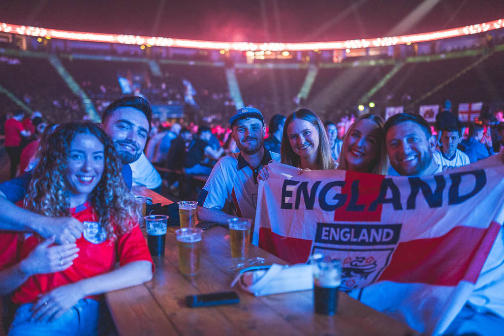 fans sat at table at ao arena manchester holding england flag and wearing england football shirts