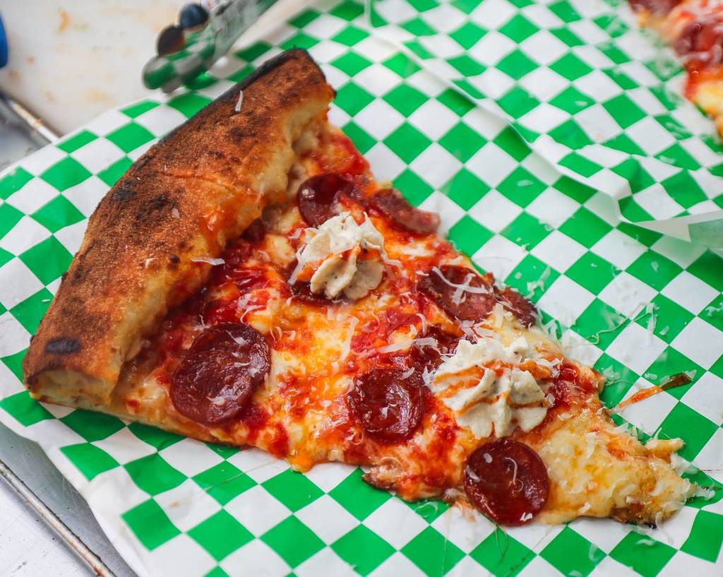 slice of pepperoni pizza by dough religion on green and white checked paper