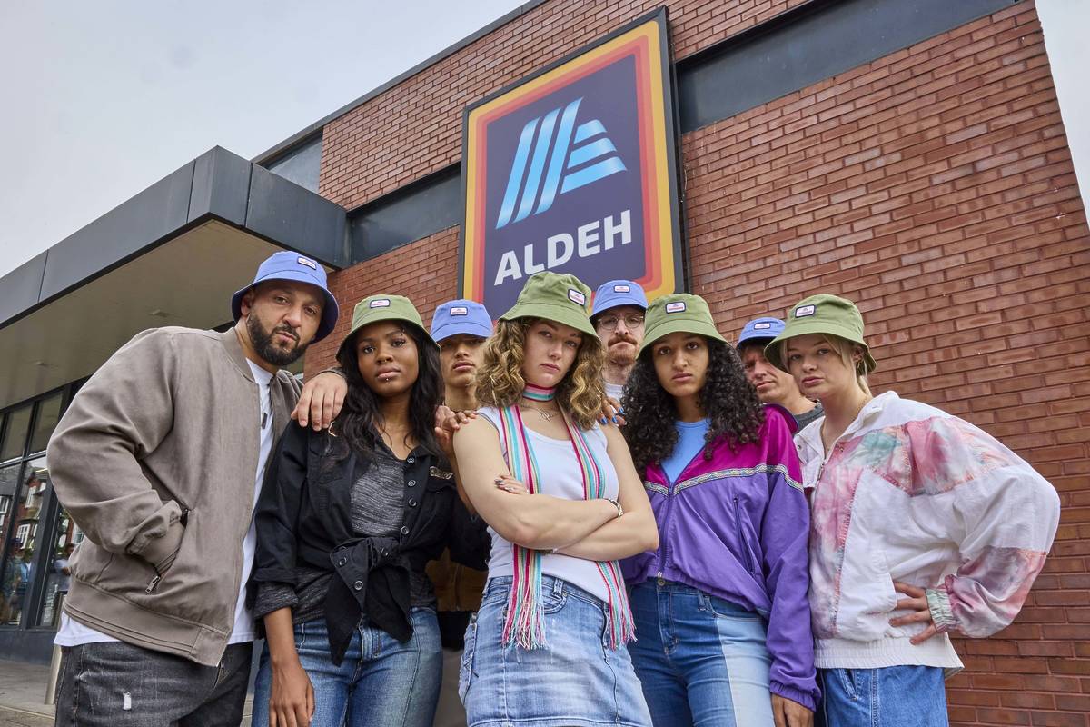 group of people with bucket hats on stood outside aldi supermarket in prestwich, manchester with sign saying aldeh, which will now be a permanent fixture