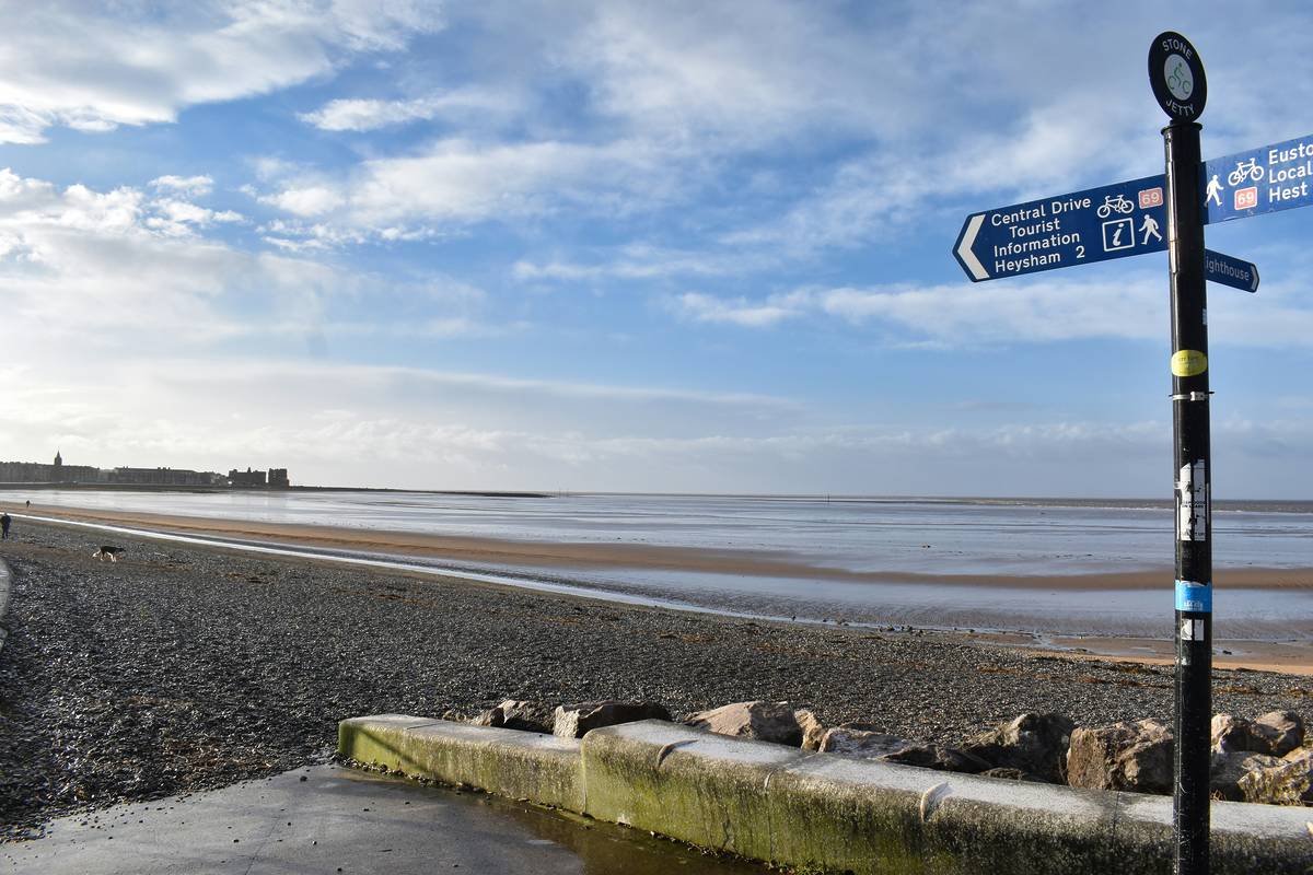 A view over Morecambe Bay from Morecambe. A signpost in view