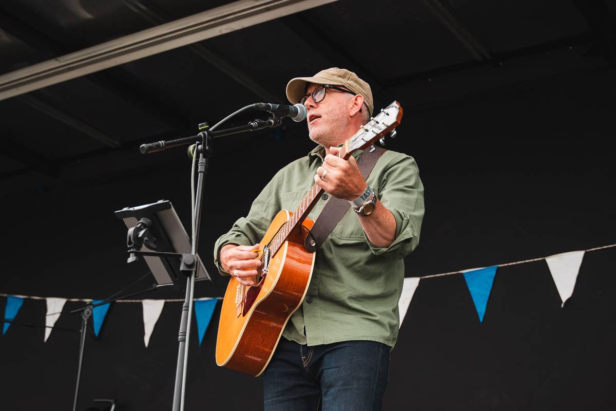 man performing on stage with acoustic guitar at heaton park food and drink festival