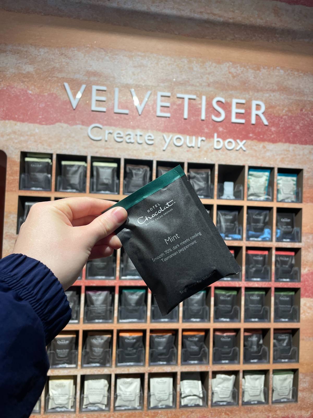 mint chocolate sachet held up in front of velvetiser wall