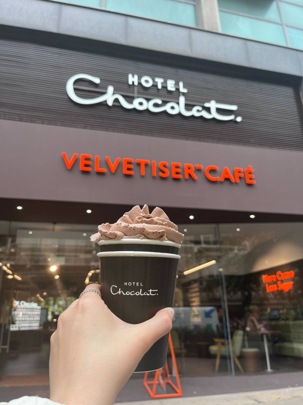 chocolate shake with cocoa whip held up outside velvetiser cafe in manchester