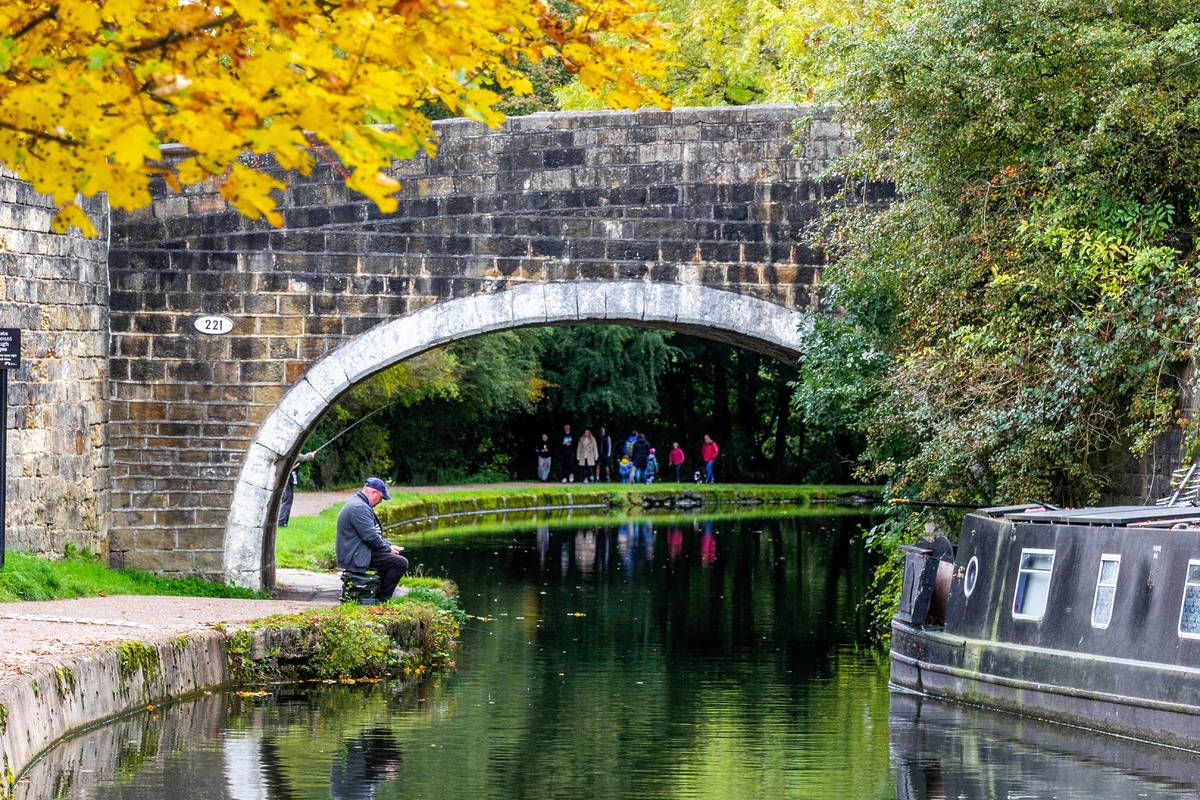leeds liverpool canal with boats bridge fisherman