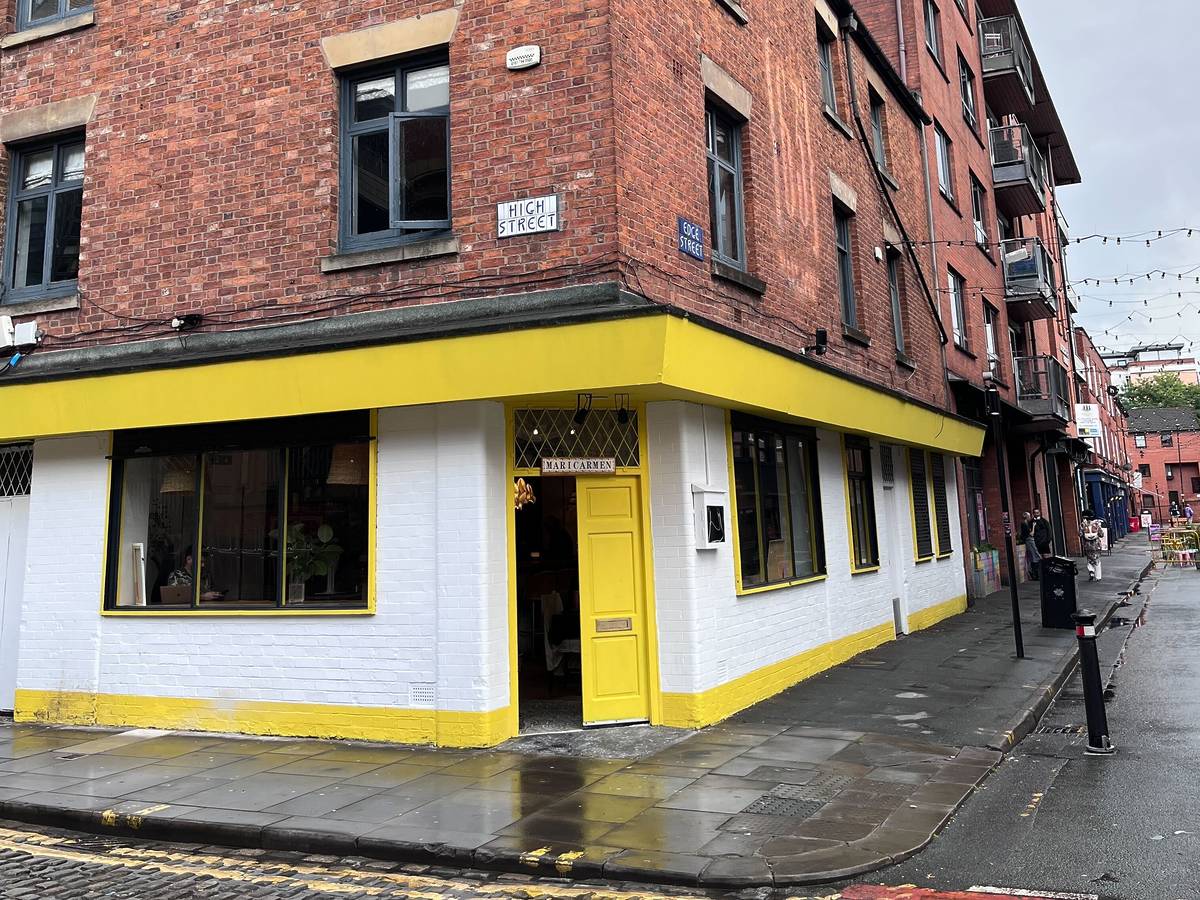 outside maricarmen restaurant on high street, manchester with cobbled streets and yellow and white frontage