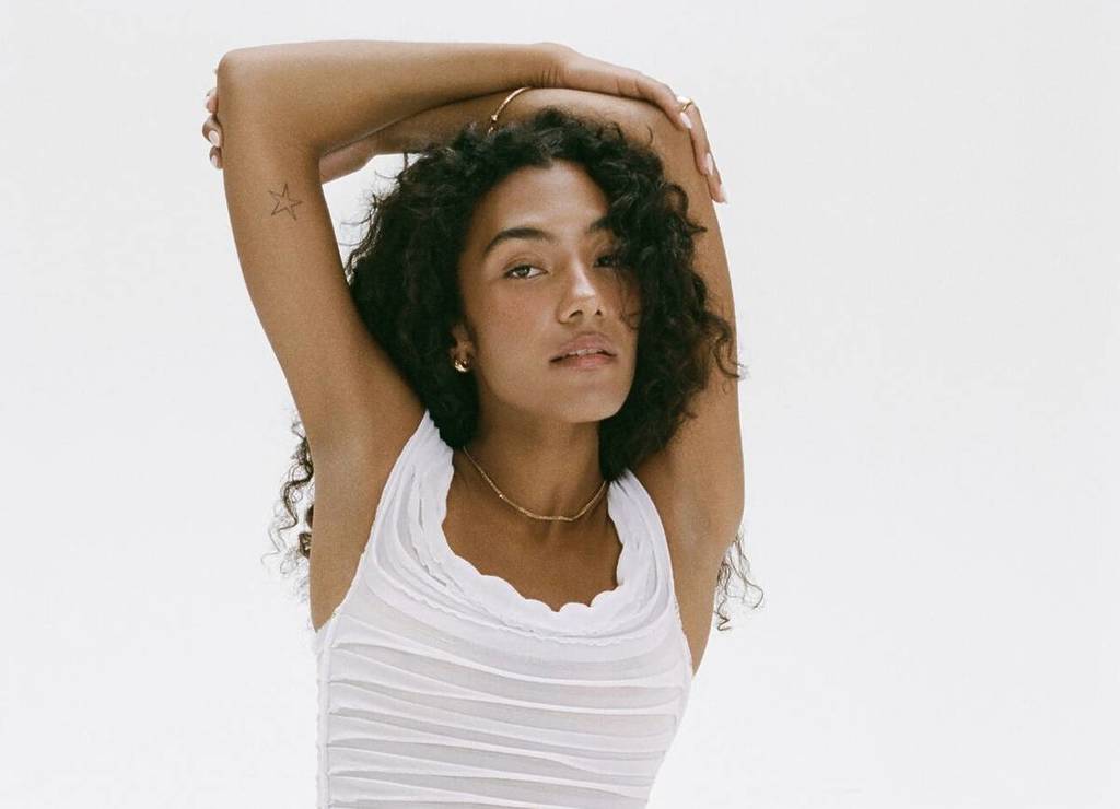 cropped image of singer olivia dean wearing white vest top