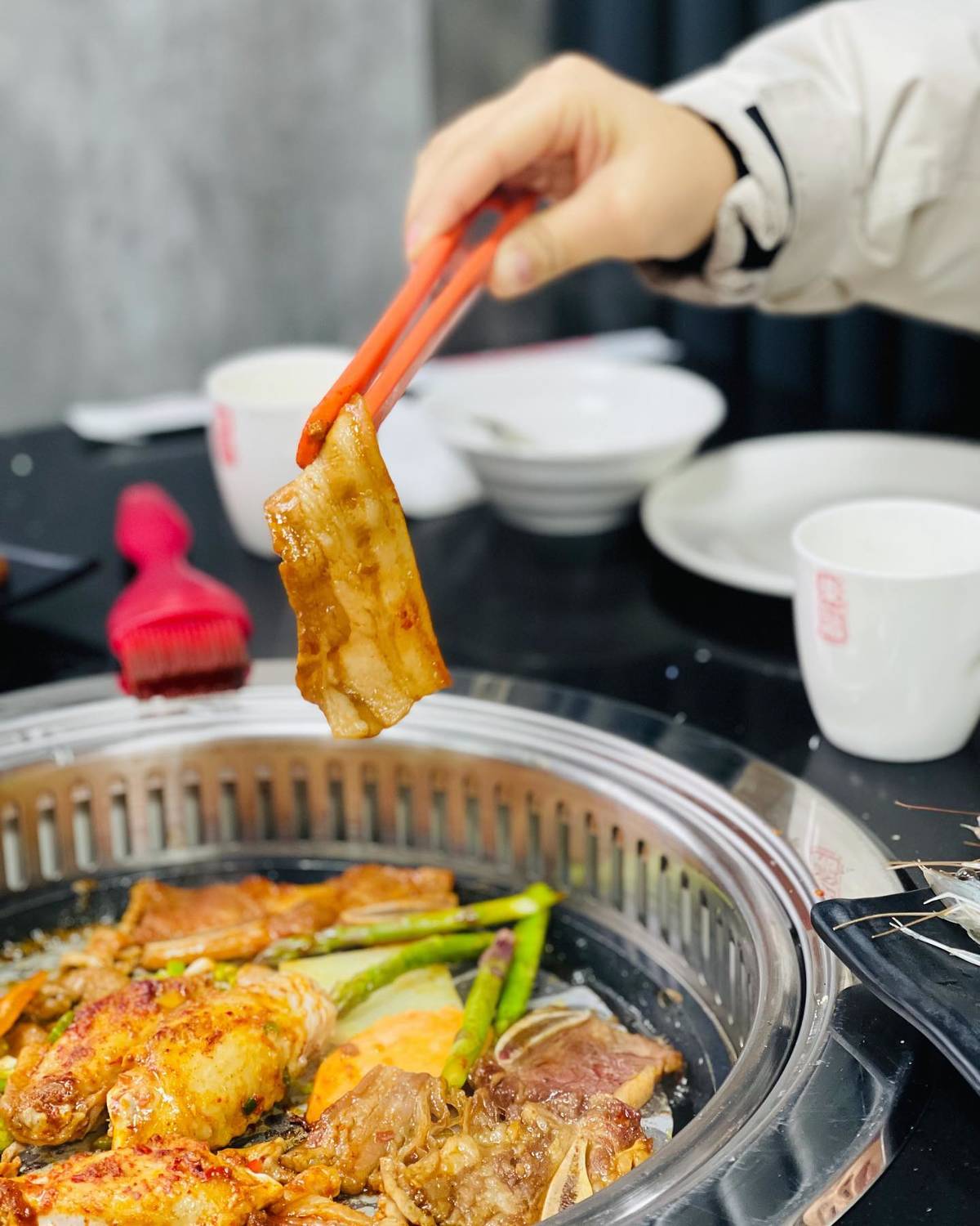 cooked meat held up with tongs at azuma manchester