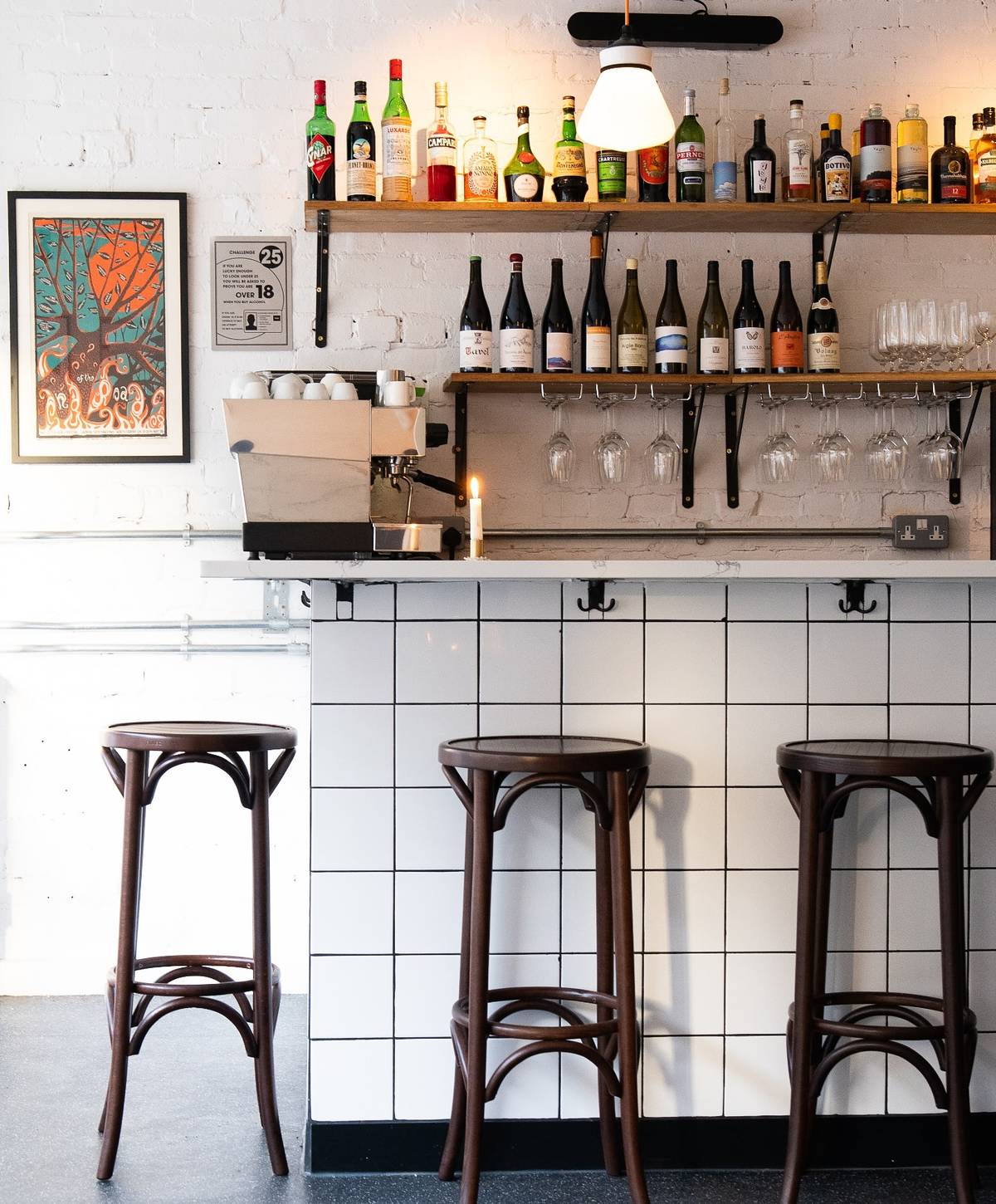 inside cantaloupe rsetaurant in stockport with bar stools and white tiles along bar and shelves of bottles above