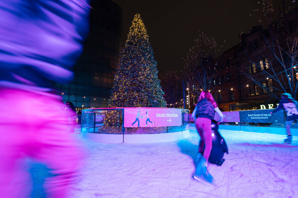 people skating around christmas tree in the centre of ice rink at skate manchester