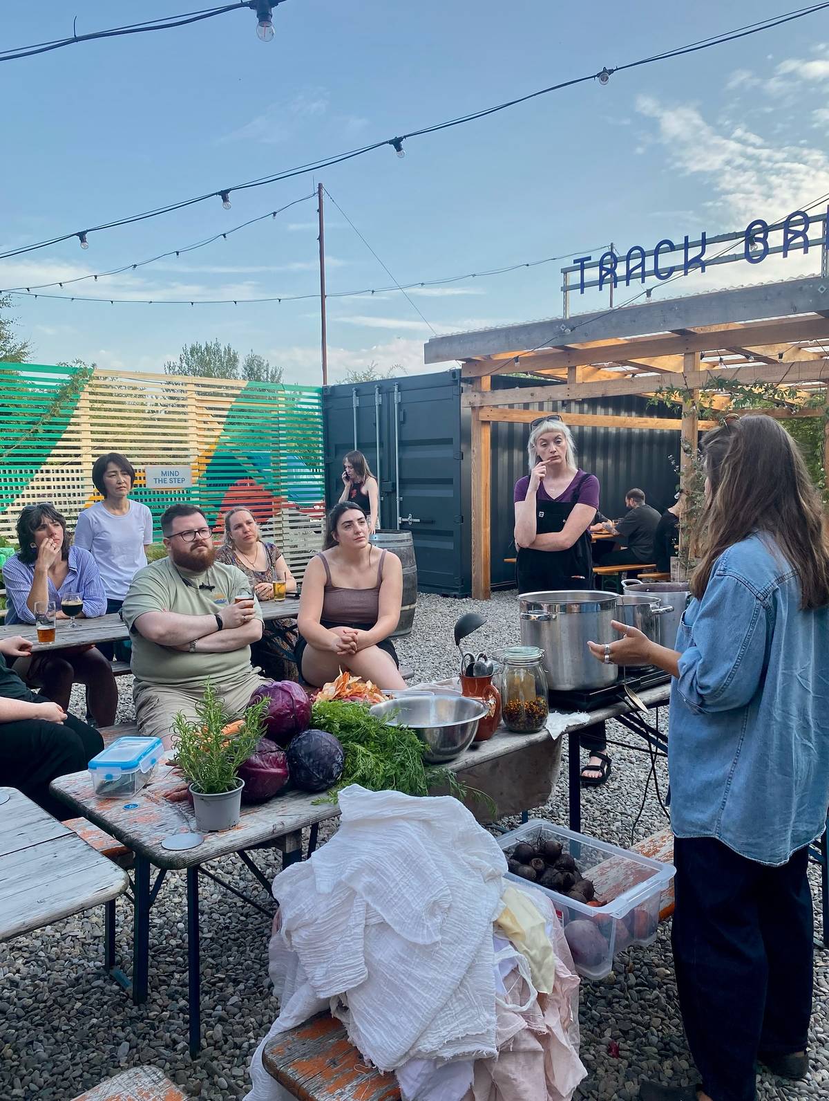 people sat outside at track brewery with veg on table for track pickle club