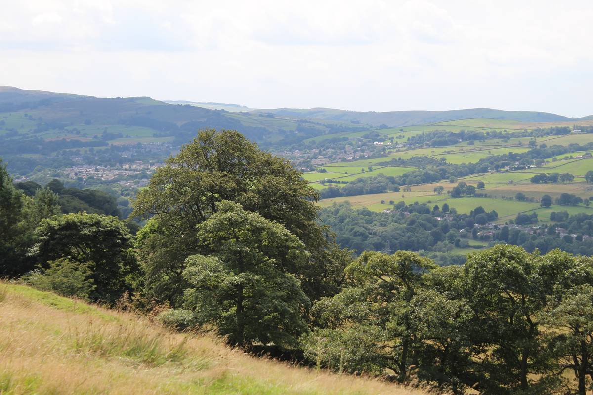 Landscape view over Whaley Bridge in the Peak District National Park. New Mills in the High Peak. Cloudy skies and trees.