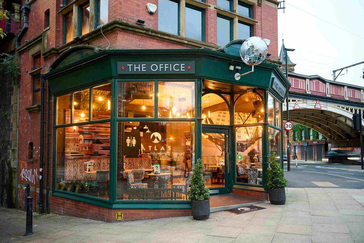 atlas bar in manchester with green frontage and the office sign