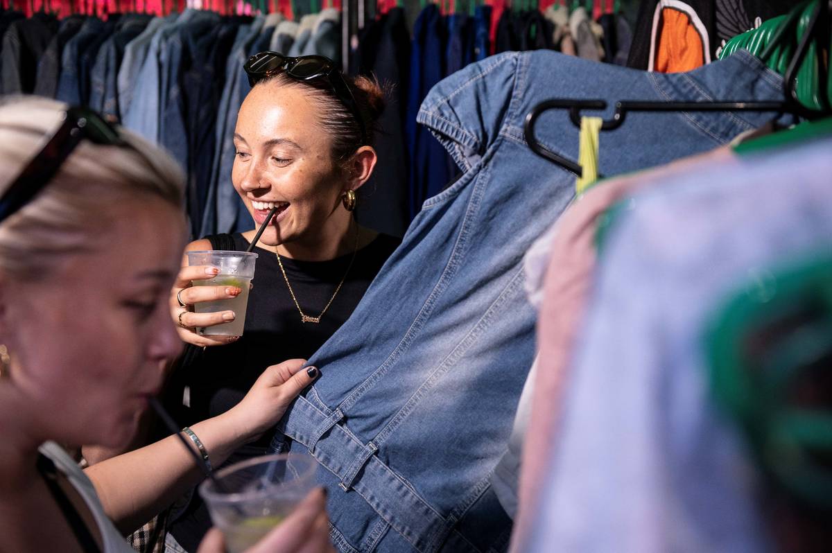 woman drinking drink whilst browsing clothes at the night market