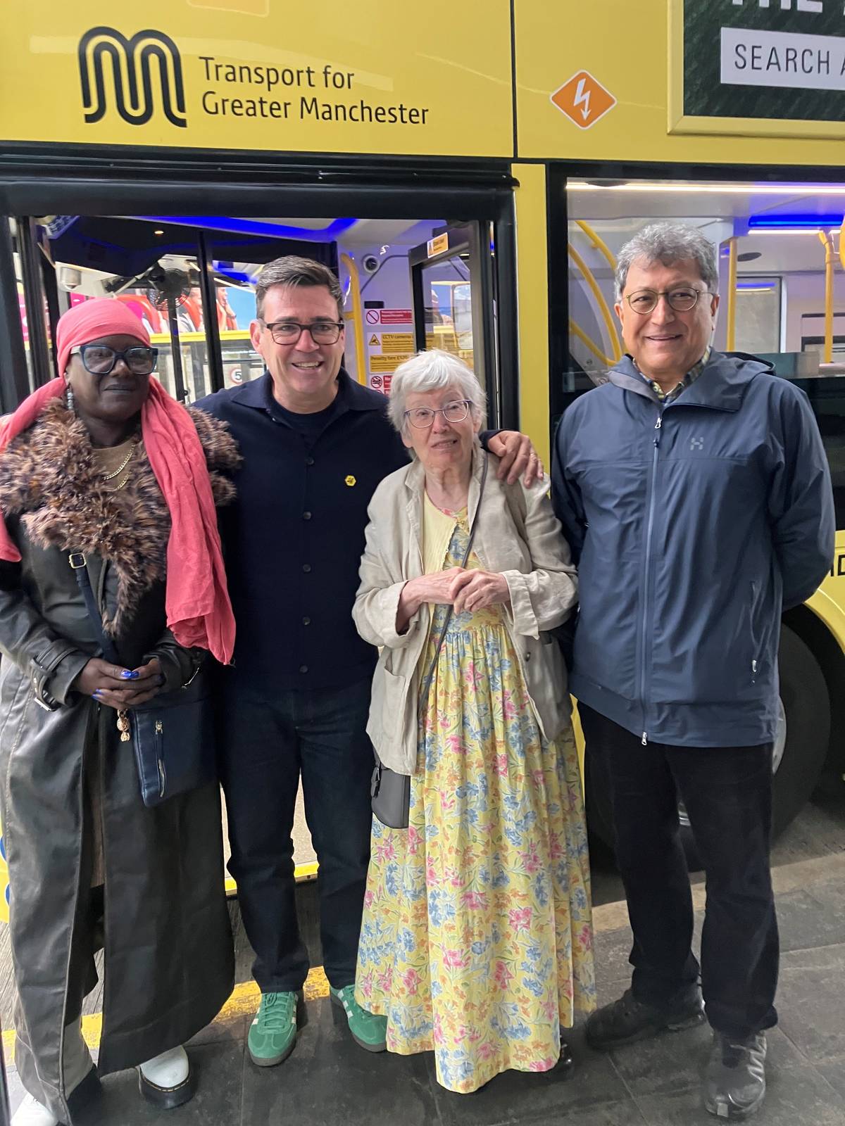people stood with andy burnham, mayor of greater manchester, in front of bus