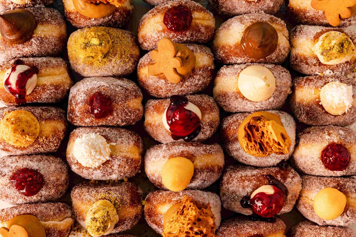 rows of bread ahead sugar doughnuts with various toppings like honeycomb, jam, custard and vanilla cream