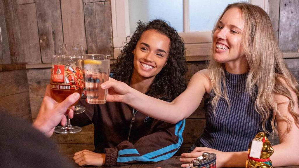 two women cheers someone of screen with pints