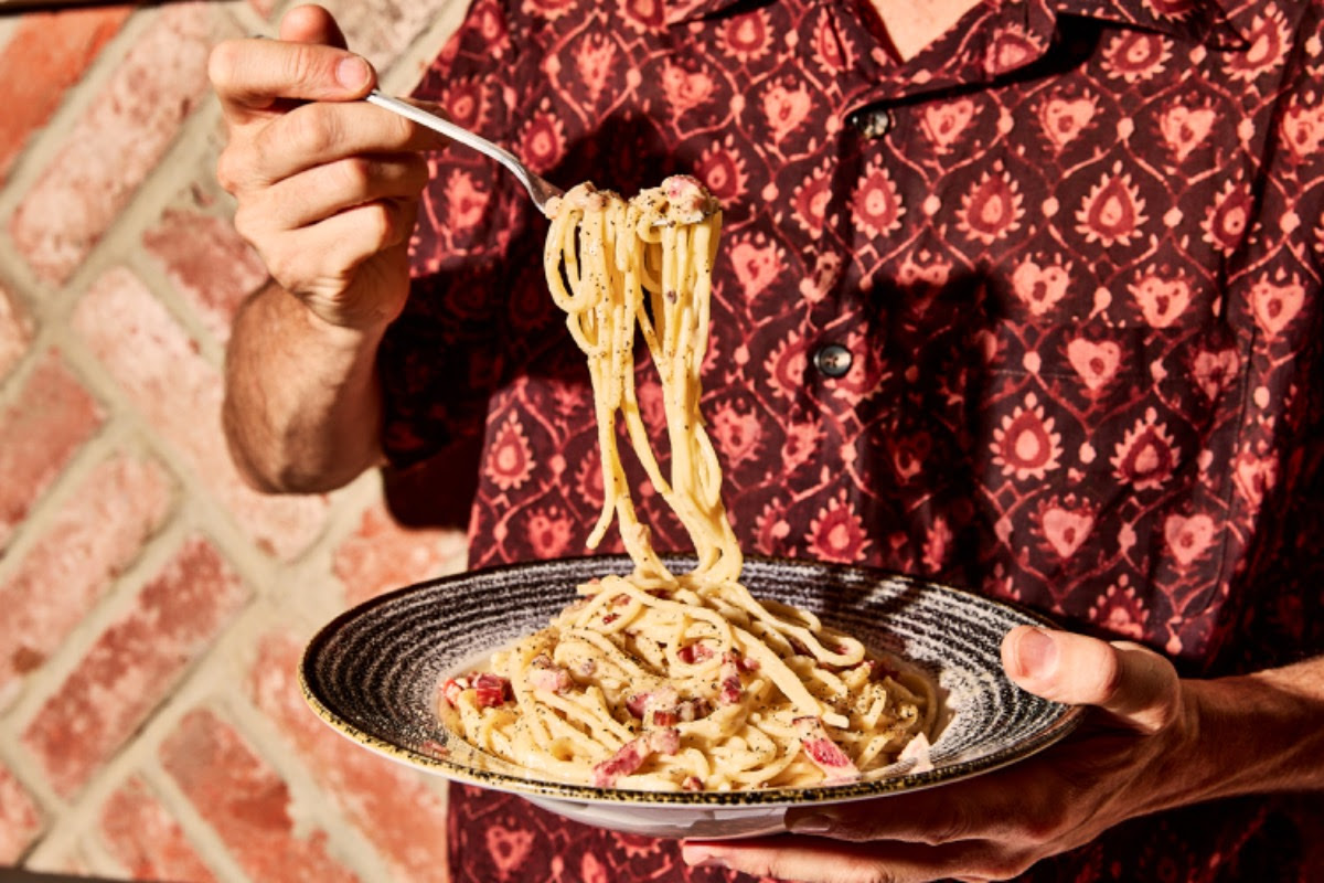 person taking spaghetti from pasta bowl at bella italia