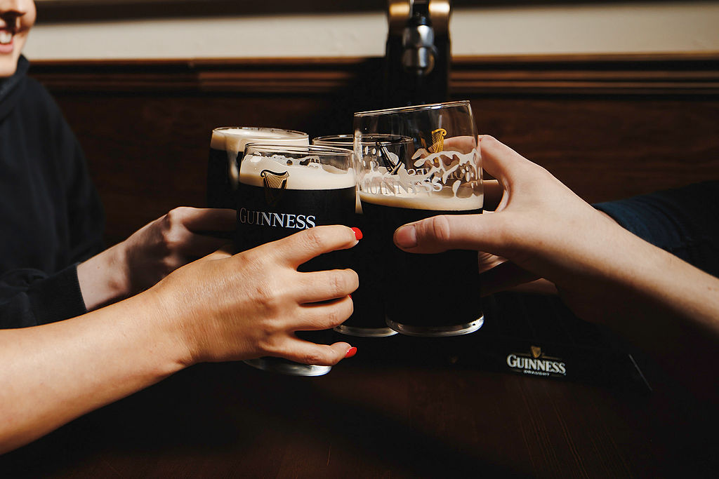 hands holding pints of guinness and cheersing at dirty o'sullivans in manchester