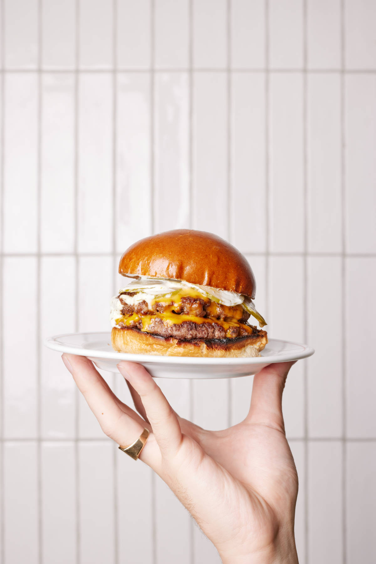 mollie's double cheeseburger being held up on pate which is the national burger awards final