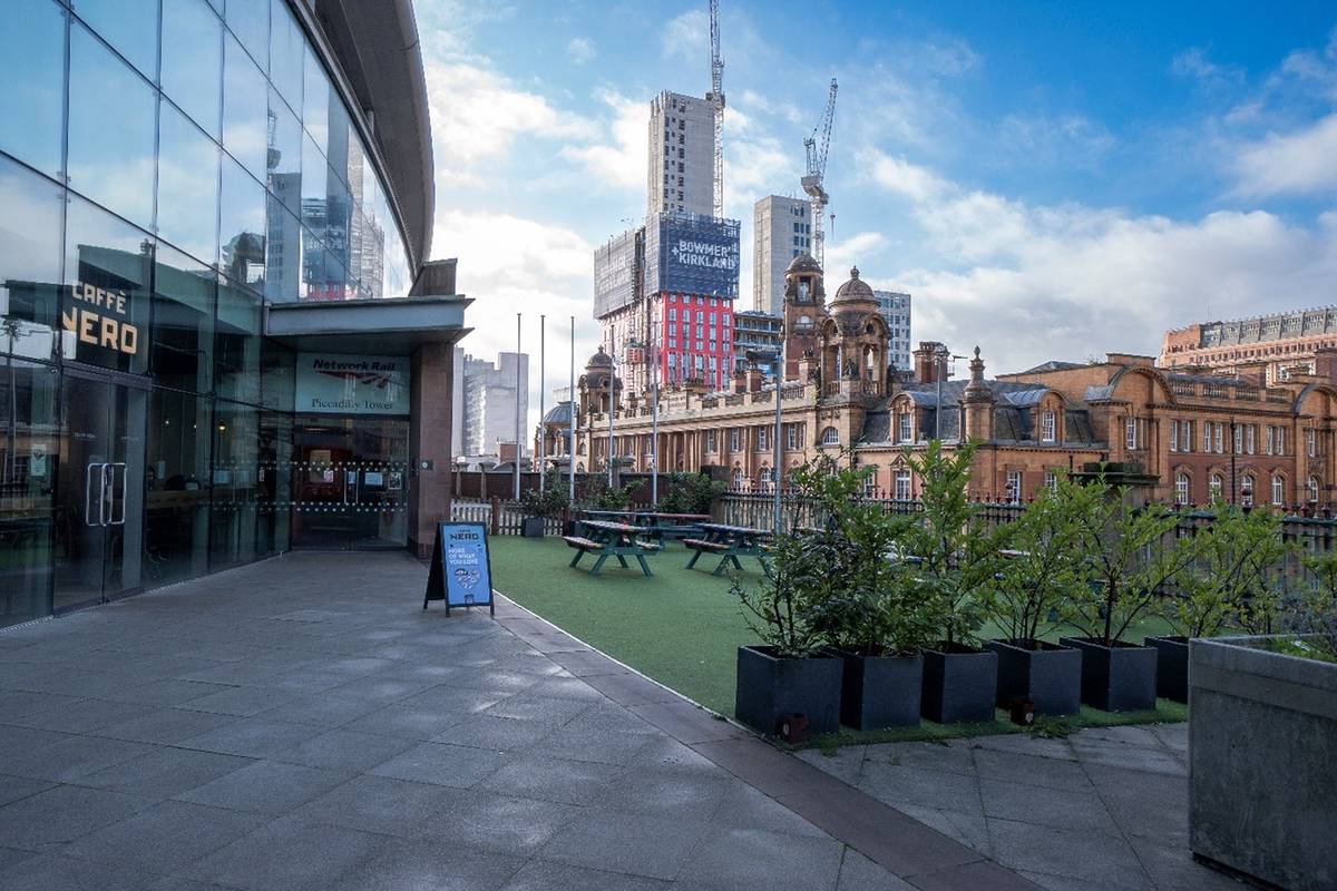 caffe nero entrance and view of red brick buildings from manchester piccadilly station garden