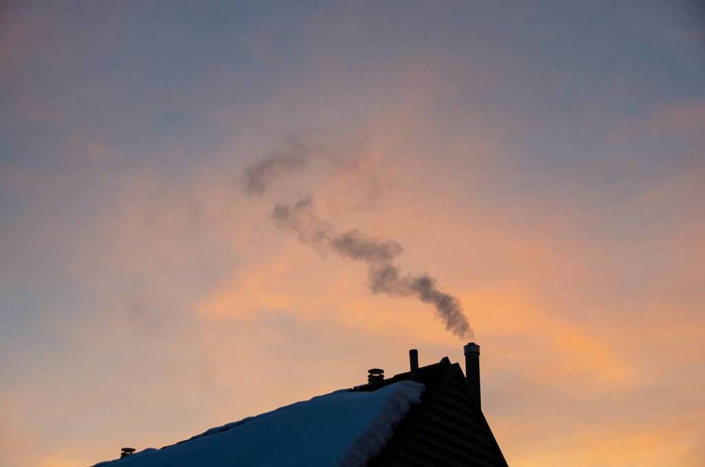 heat coming out of chimney of hosue with snow on roof