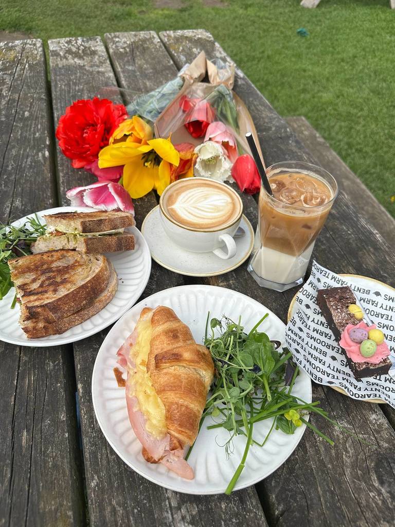 coffees, tulips, croissant, toastie and chocolate cake on wooden table