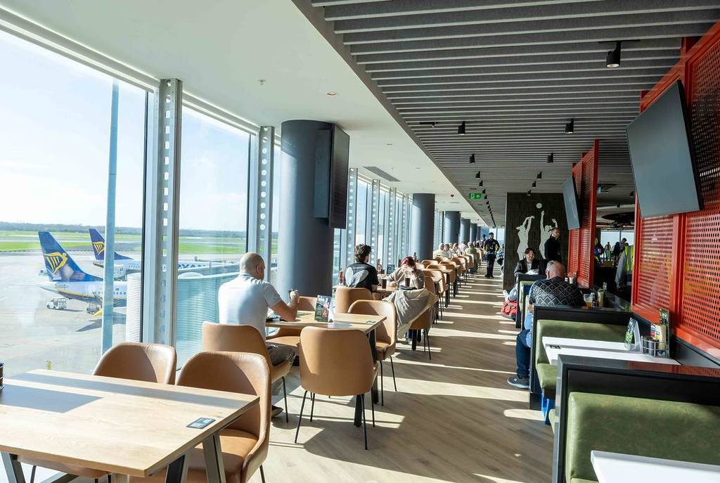 rows of tables and chairs by windows looking out to airport runway