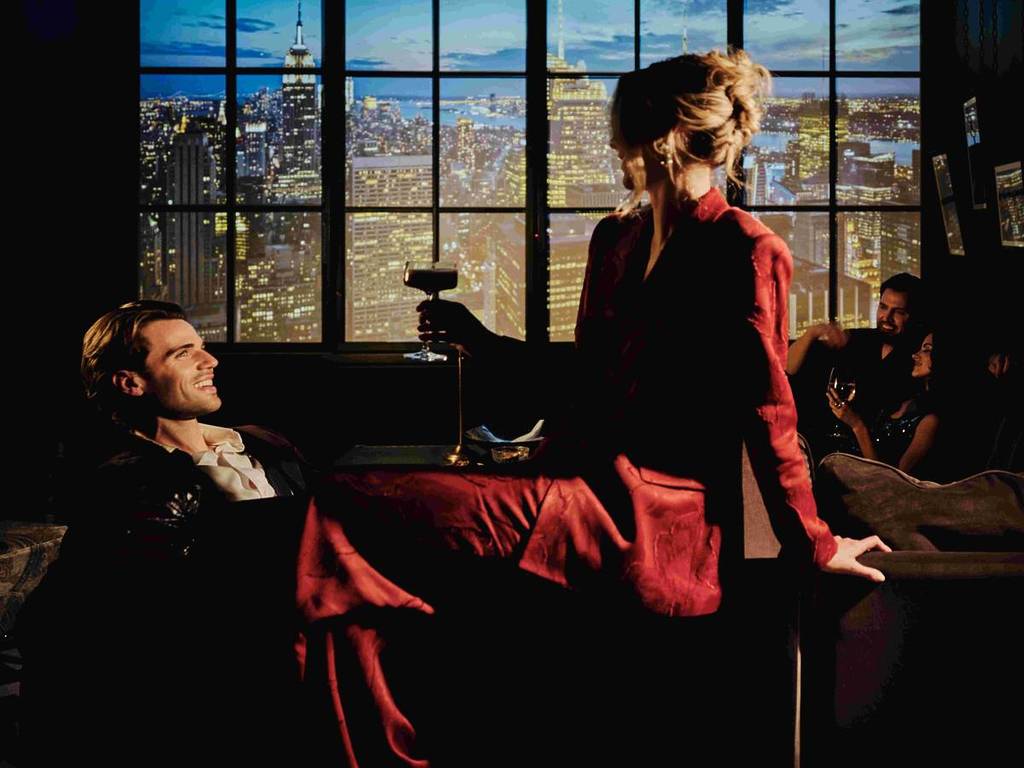 couple sat at the rex hotel with views of manchester at night in background