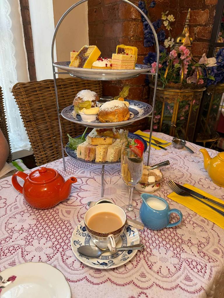 afternoon tea with tiers of cakes, sandwiches and scones next to tea