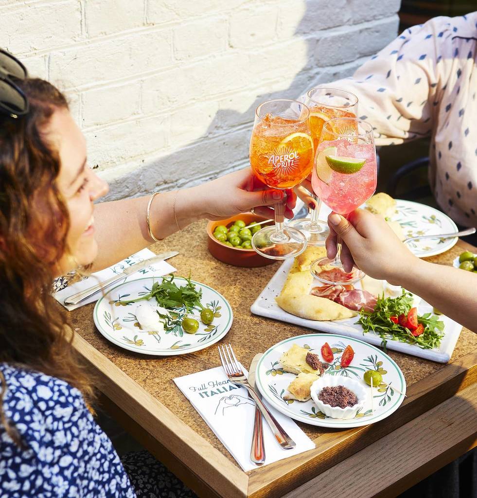 ask italian meal with women cheersing aperol spritz