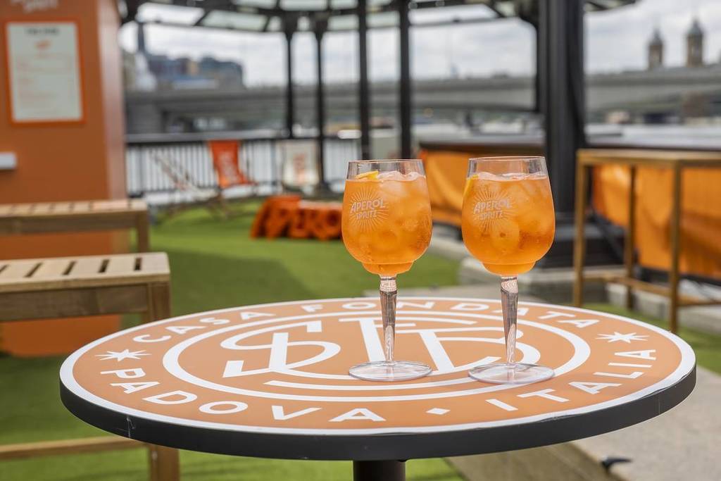 two aperol spritz on a garden table at a rooftop bar