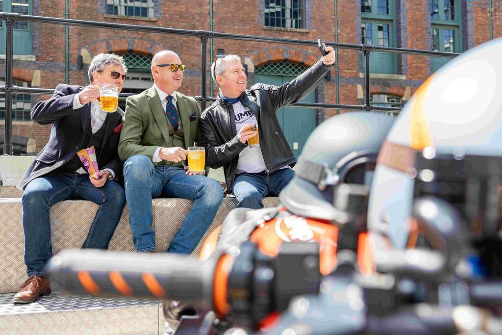 men sat with pints of beer in st john's manchester next to motorcycles