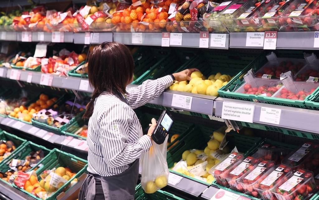 person stocking fruit at waitrose store