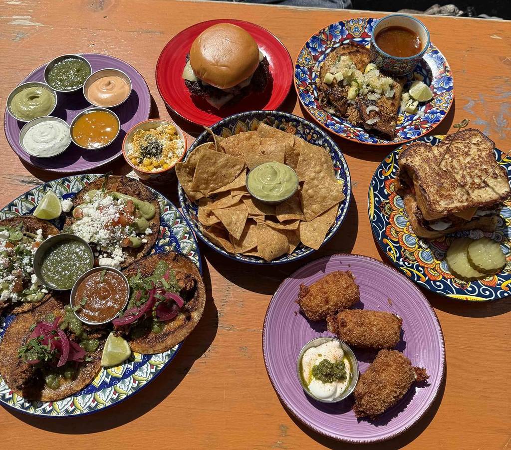 selection of plates on table including tacos, smash burgers, texas toast, tortilla chips and salsas