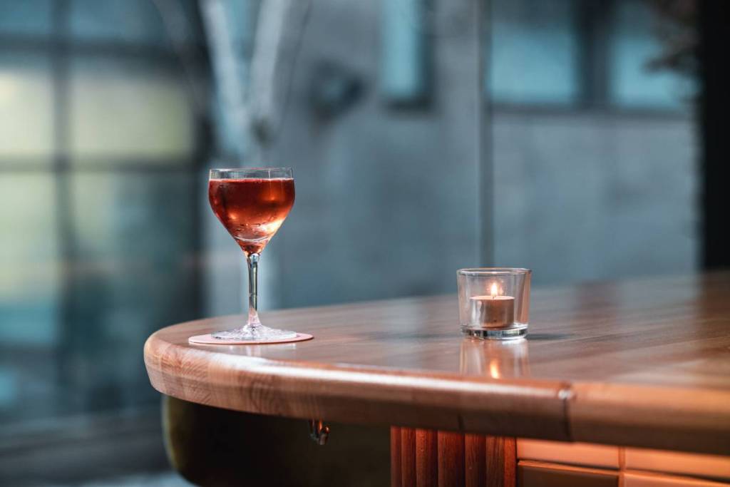 cocktail on side of bar next to candle at posie in manchester, which ahs been added to the michelin guide