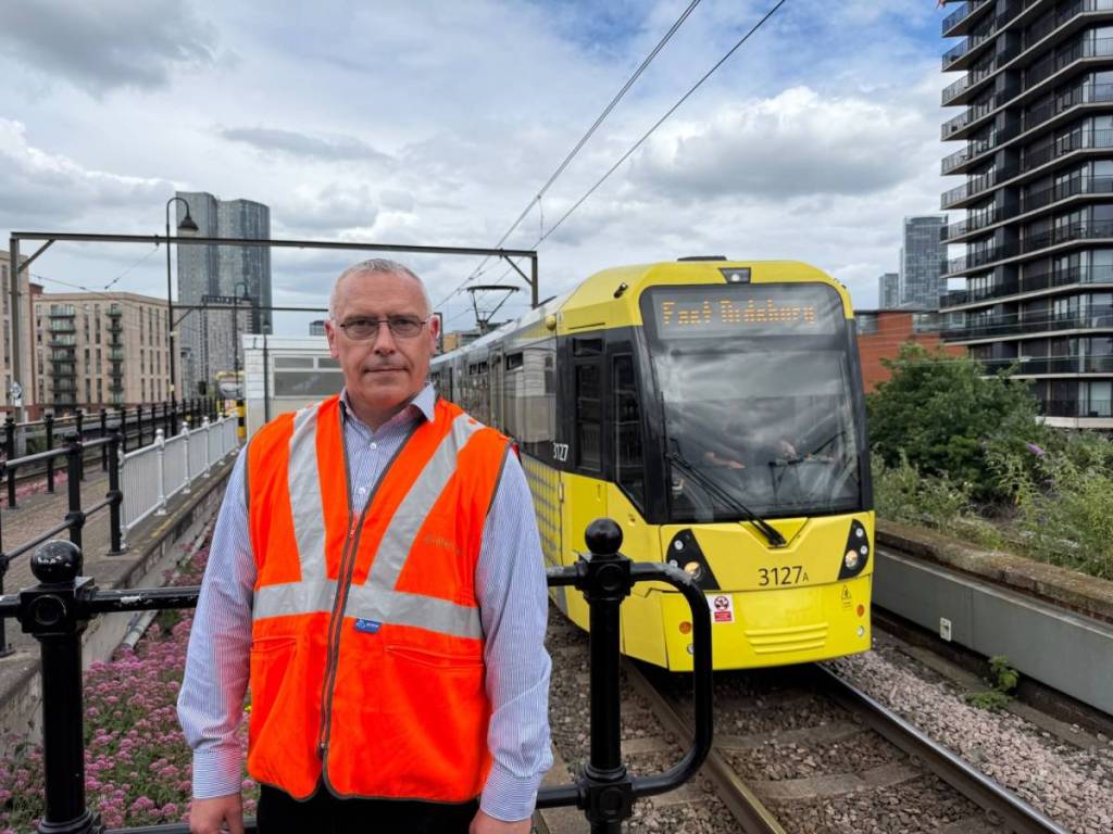 engineer with hi-vis on stood in front of tram at cornbrook