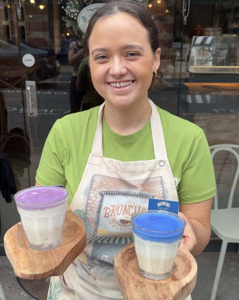 woman at bruncho cafe holding two frozen drinks - one blue matcha, one ube