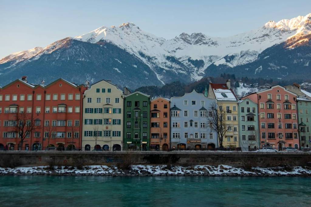 colourful houses in row in innsbruck with alps in background