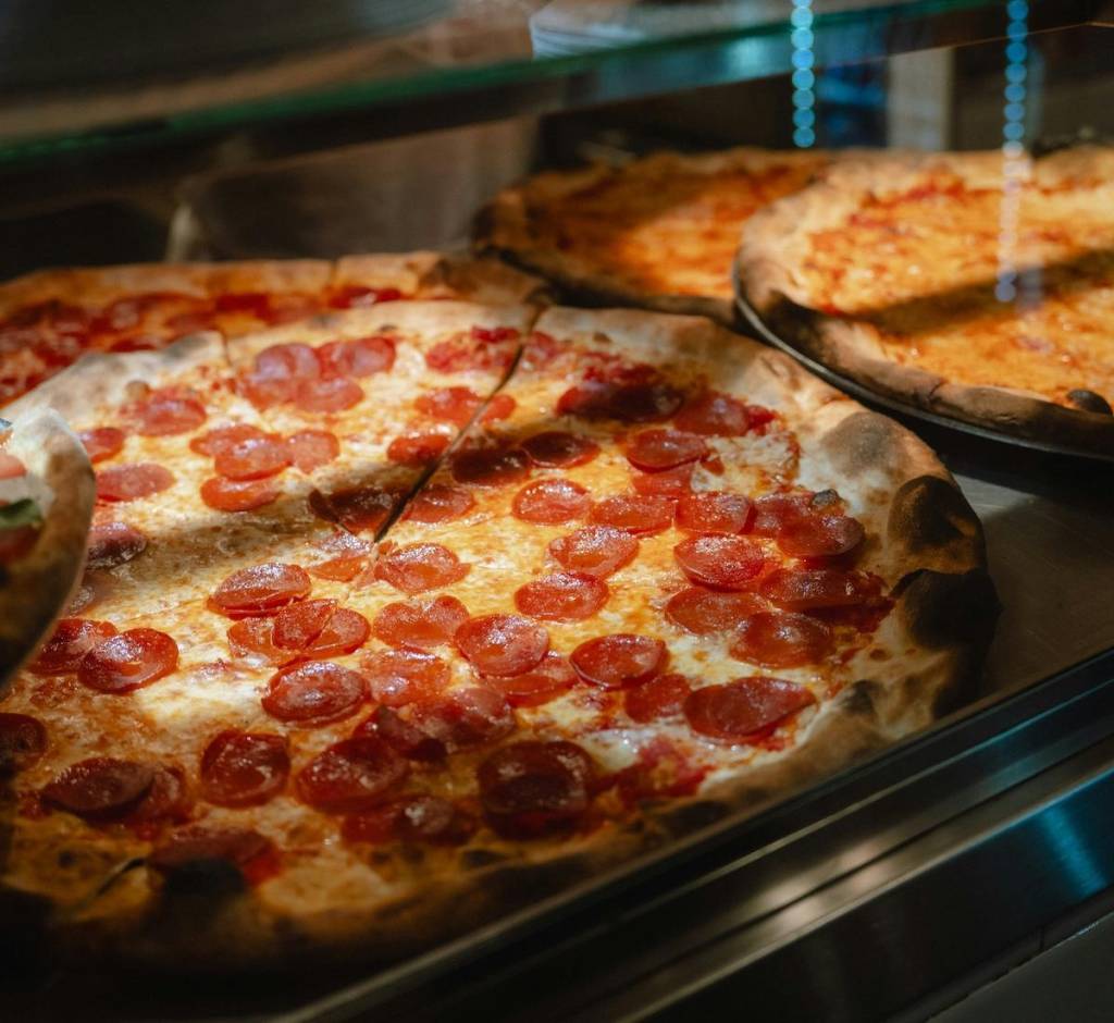 pepperoni pizza behind glass at a pizza parlour counter