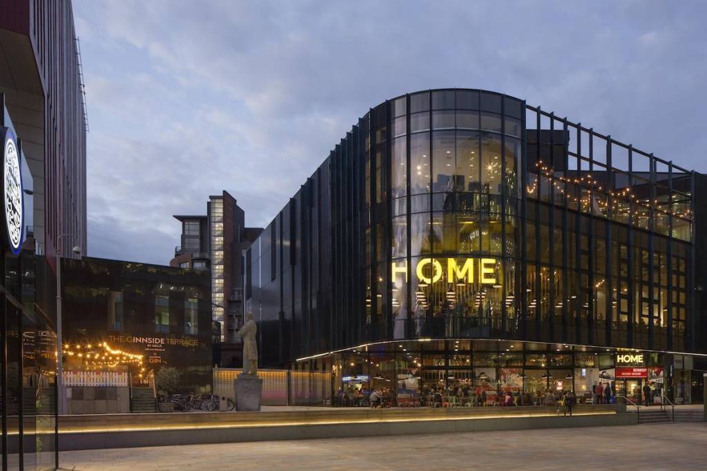exterior of the Home arts centre in manchester in the evening with all the lights shining through the building