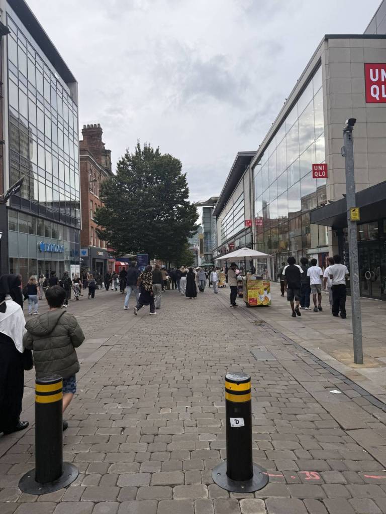 people walking down market street in manchester near uniqlo store